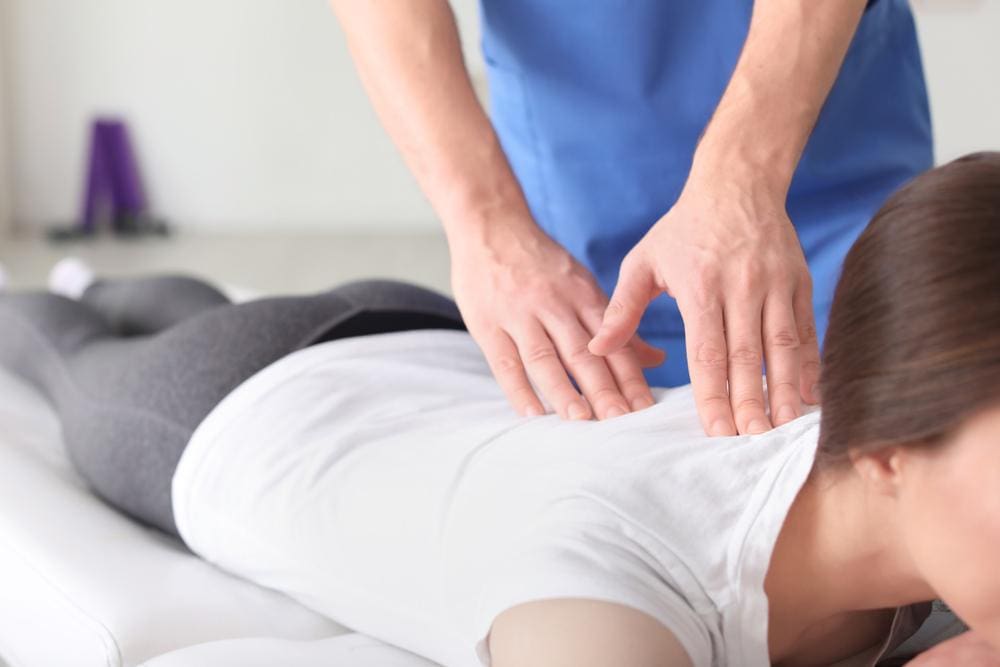 A chiropractor works on the spine of a female patient to improve posture. 
