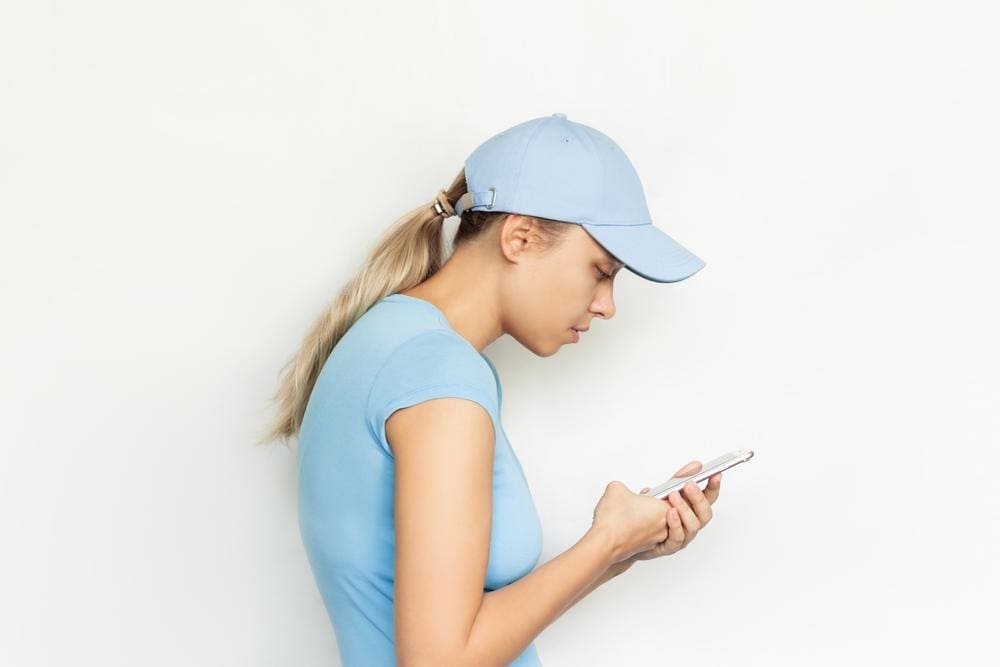 Young woman hunched over looking at phone.
