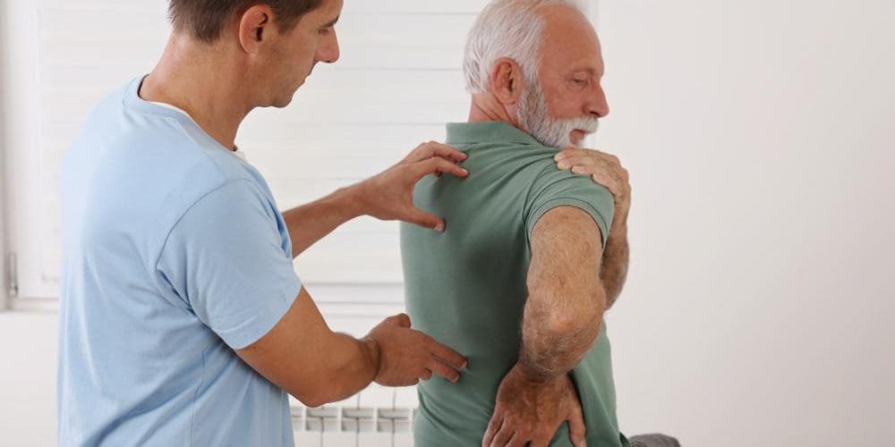 Senior man with back pain being examined by chiropractor.