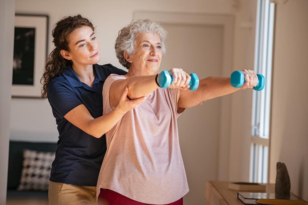 Chiropractor working with senior woman doing physical therapy with weights. 
