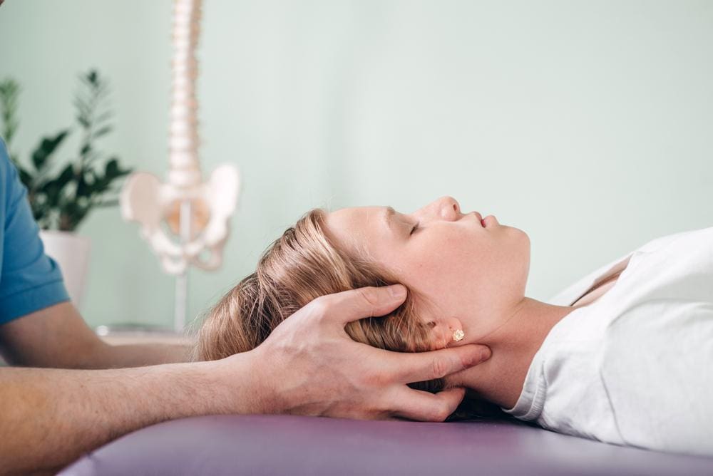 Young woman with vertigo getting neck massage from a chiropractor.


