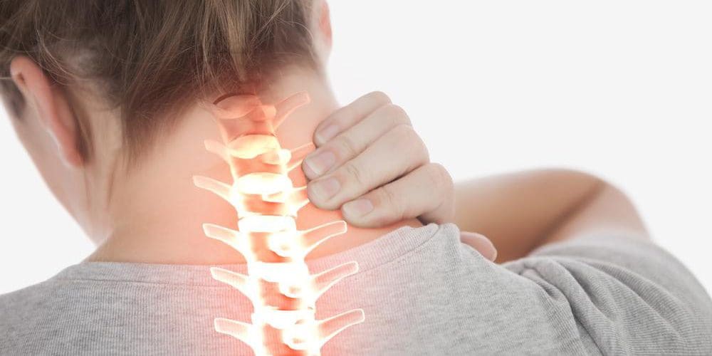 Woman suffering from bulging cervical disc grasping the back of her neck.