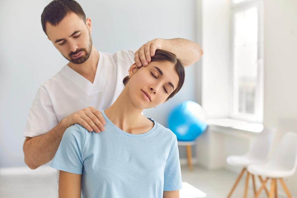 Chiropractor working on neck and shoulder of young female patient.