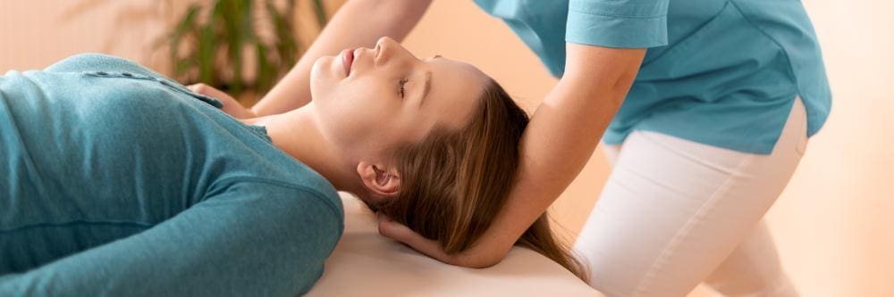 A woman is getting a neck adjustment to treat Occipital Neuralgia. 