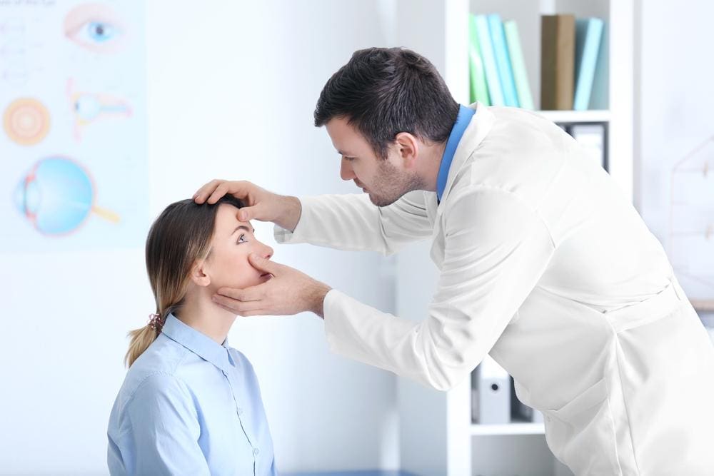 Doctor examining eye of female patient in medical clinic.