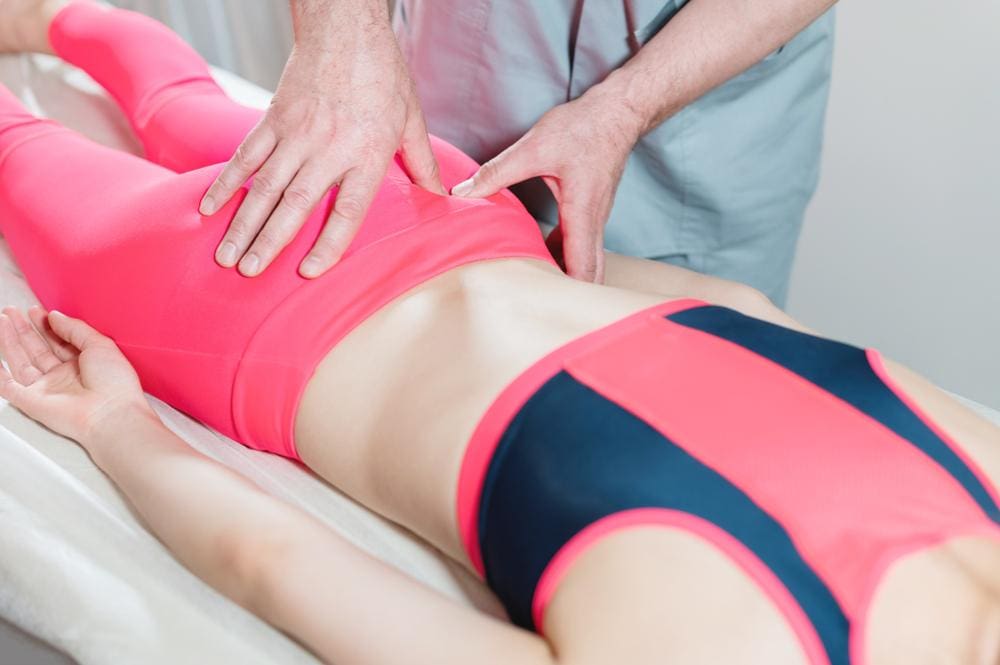Young athletic woman getting her coccyx adjusted by chiropractor.