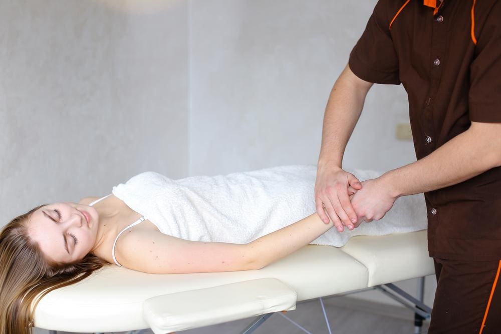 Chiropractor adjusting and massaging wrist of female patient who suffers from Radiculopathy. 