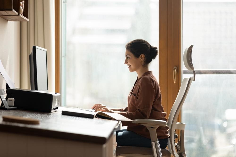 Young woman sitting up straight in ergonomic chair at desk.