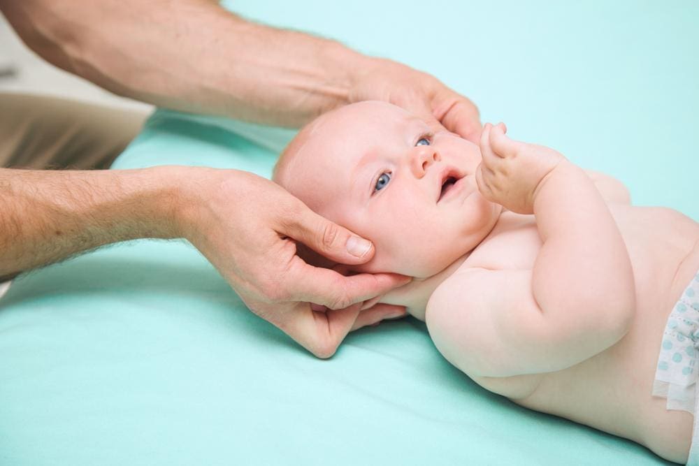 Young baby getting gentle neck massage by chiropractor.
