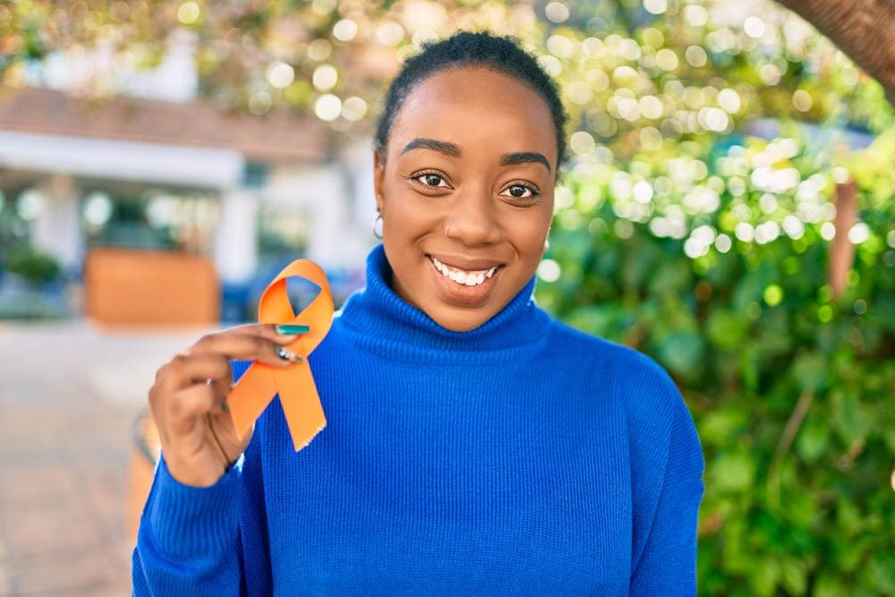 Young woman holding an orange MS ribbon.