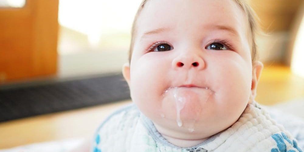 Baby with formula running down her chin.