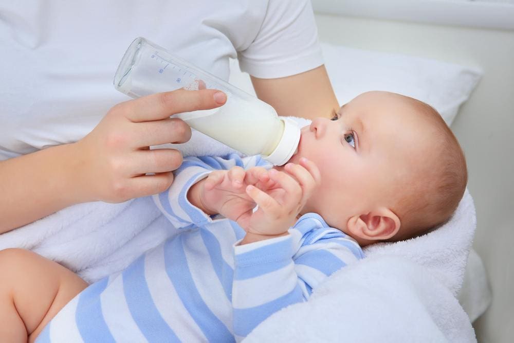 Mother holding baby and feeding him with a bottle.