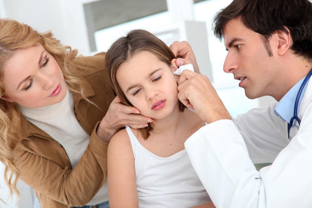 Doctor assessing young girl's ear.
