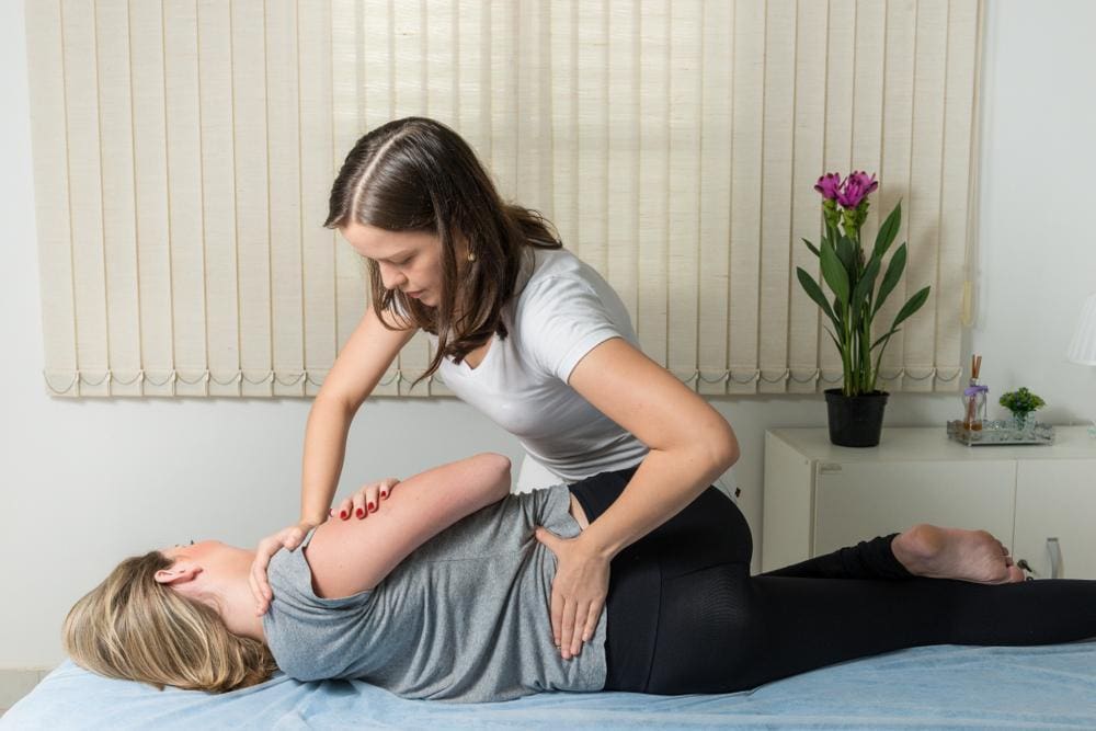 Chiropractor adjusts a young women's spine.
