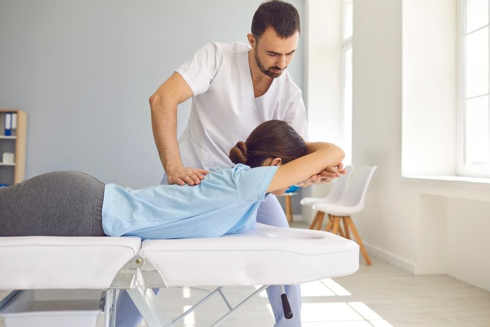 A woman is getting a chiropractic adjustment to help with flexibility in her back.