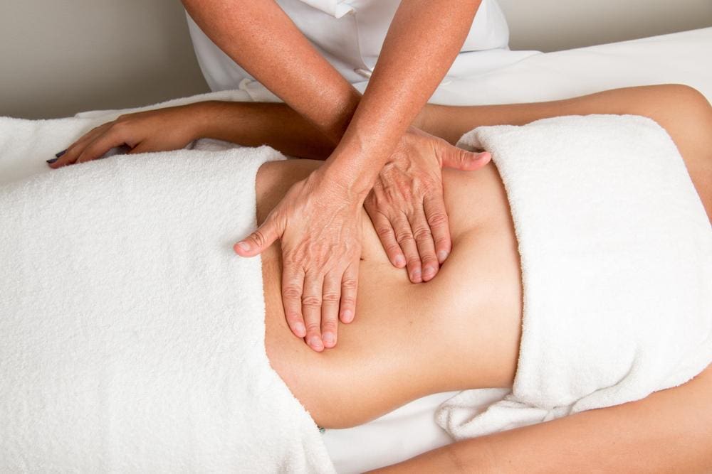 Chiropractor massaging woman's stomach.
