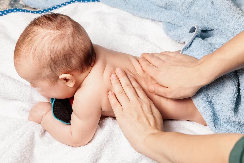 Five-month-old baby receiving back massage from chiropractor.