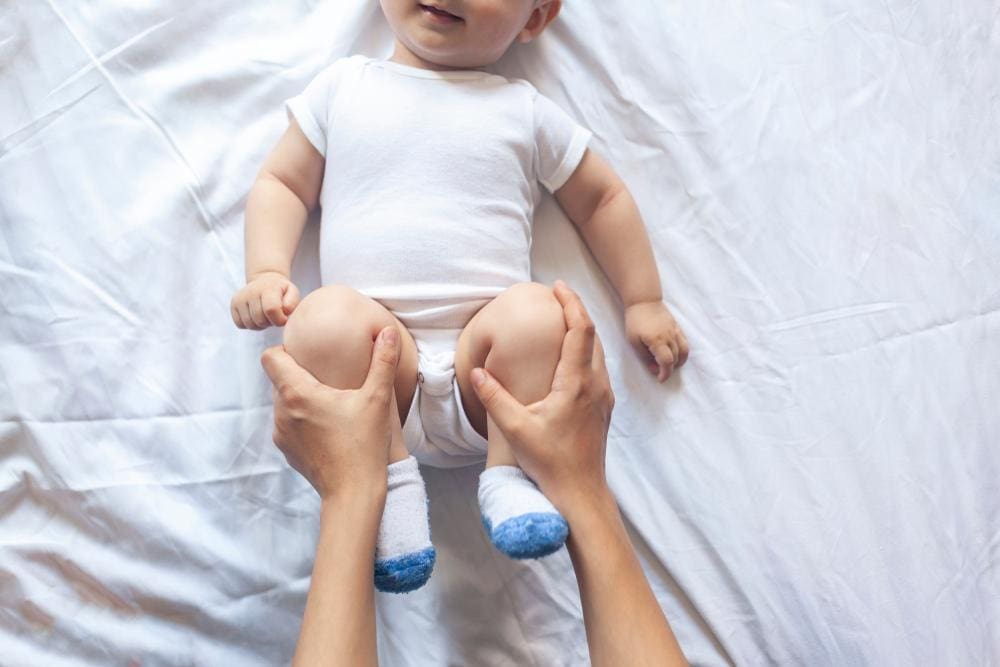 Mom doing hip exercises with her baby.