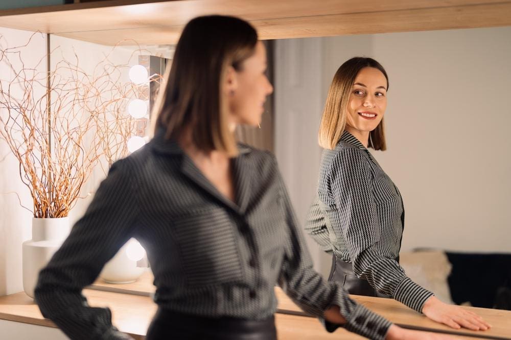 Woman looking at herself in the mirror with confidence.