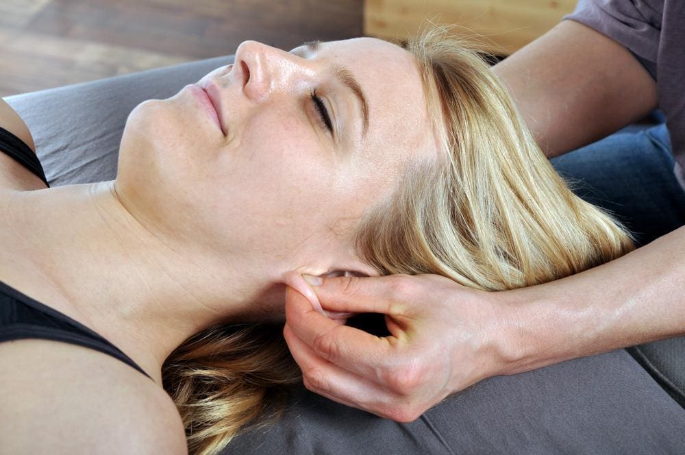 Chiropractor adjusting a woman's ears.