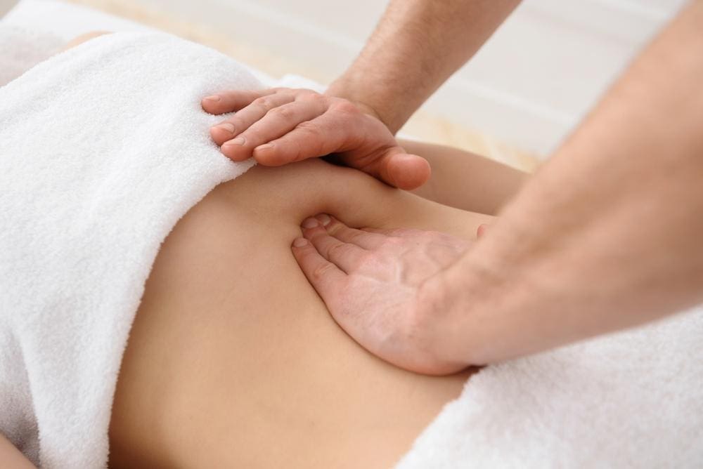 Chiropractor massaging a woman's stomach.