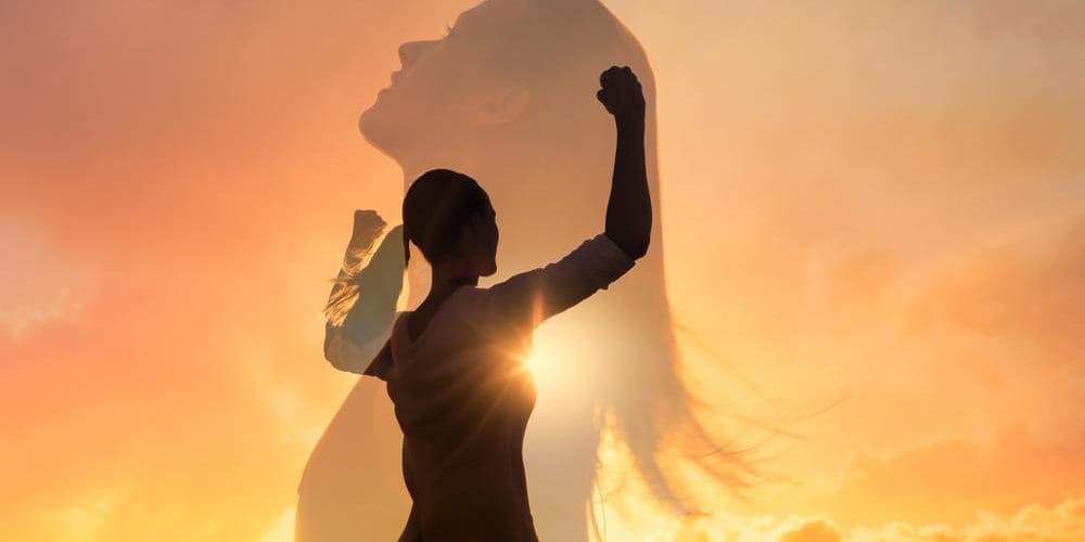 Woman celebrating and feeling confident against a sunset.