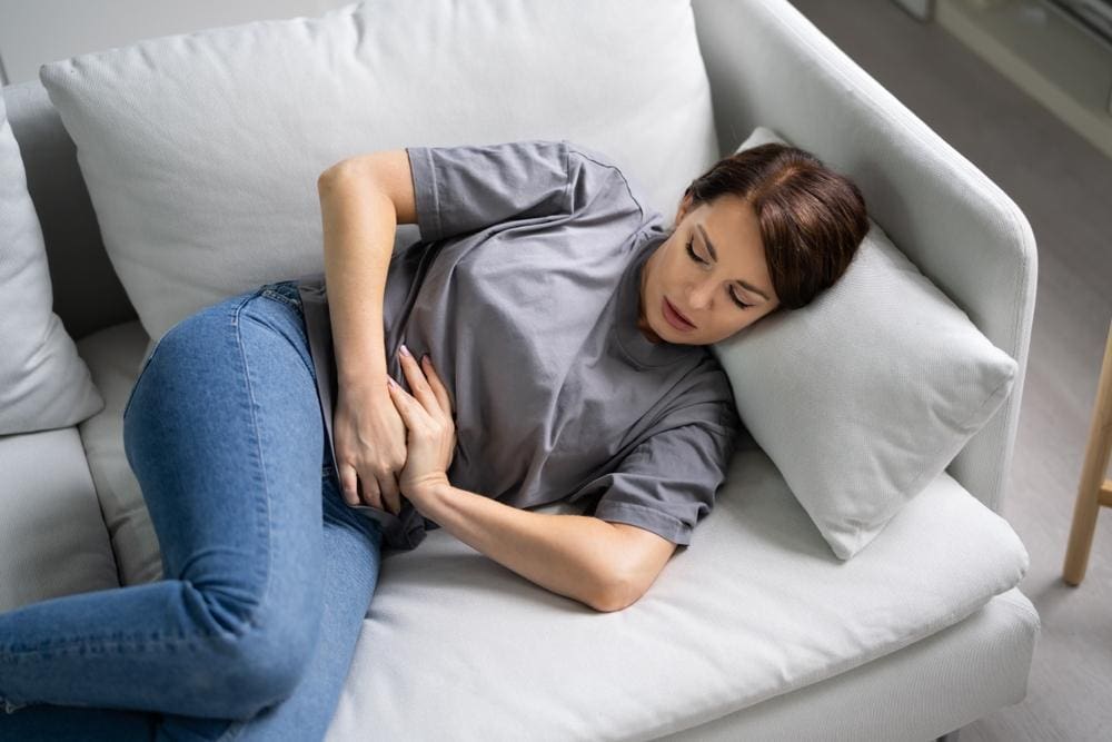 Woman lying on couch with abdominal pain.