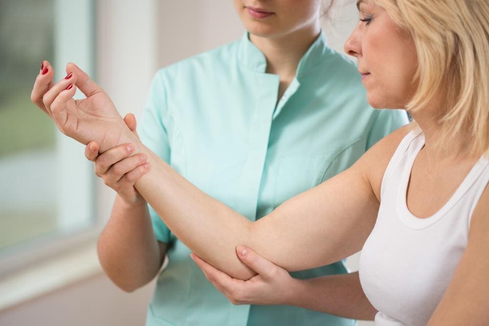 Healthcare professional checking a patient's right arm and elbow.