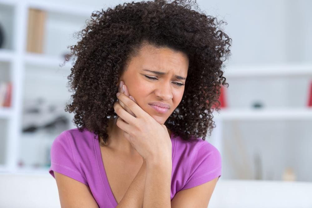 A young woman is experiencing jaw pain.