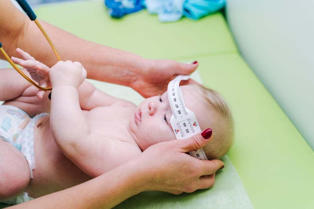 Healthcare provider measuring infant's head.