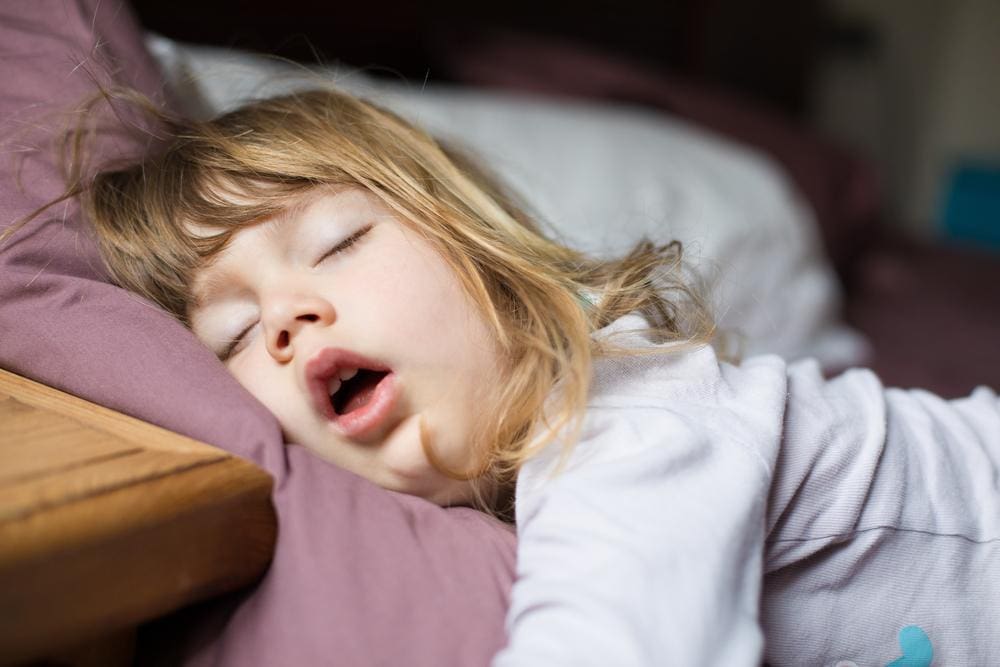 Little girl sleeping soundly with her mouth open.