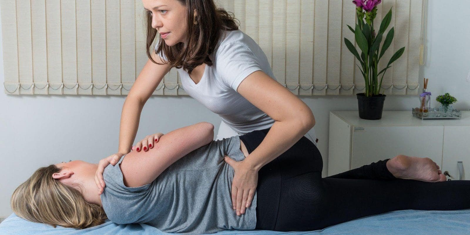 Chiropractor working on a young woman's lower back.