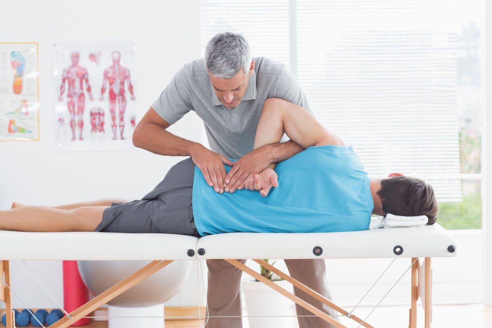 Chiropractor working on a young male patient's lower back.