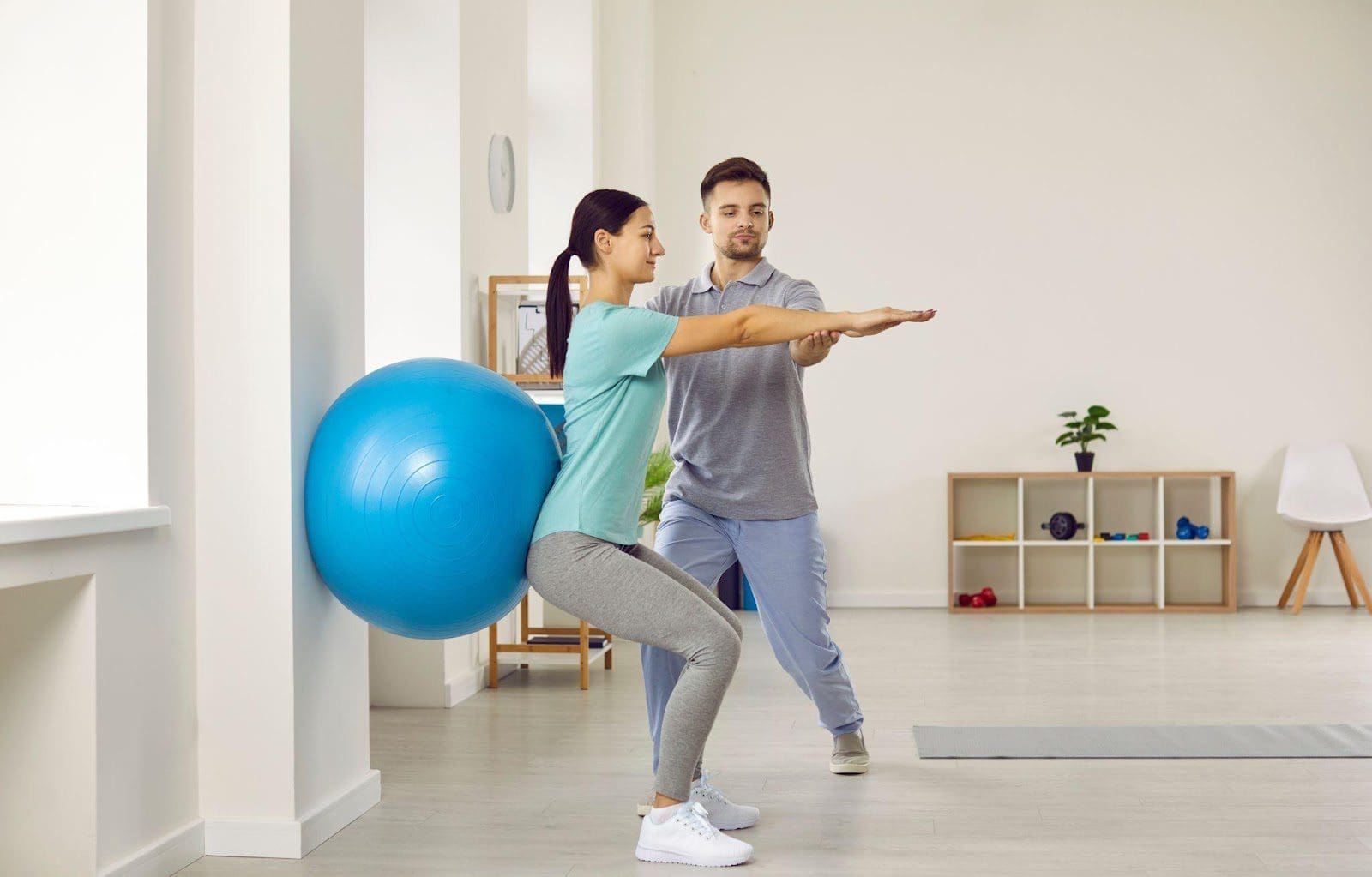 Chiropractor coaching a woman who is using an exercise ball.