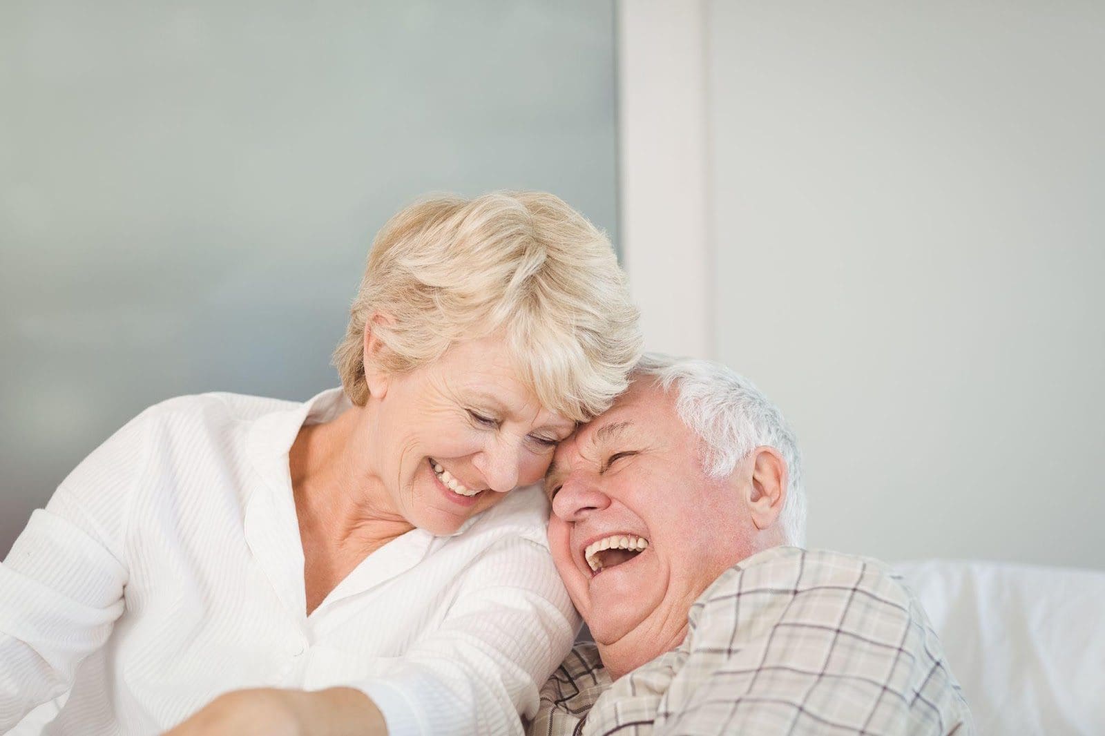 Happy senior couple sitting on a bed at home.
