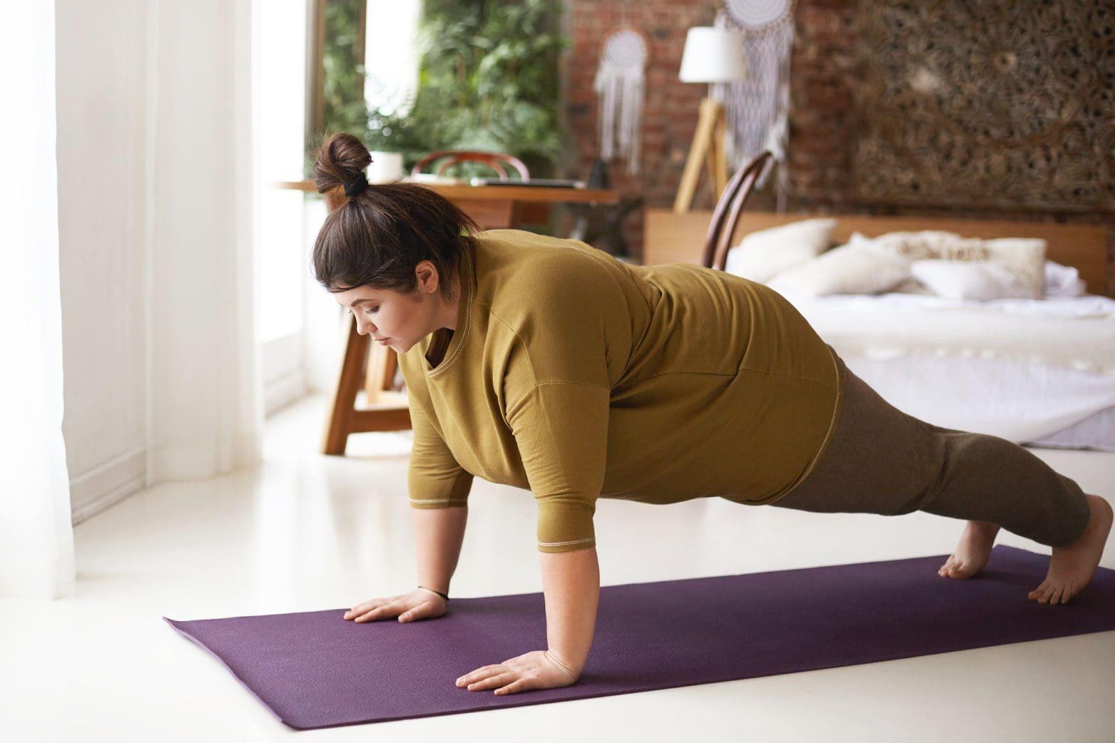 Plus-sized woman doing yoga at home.