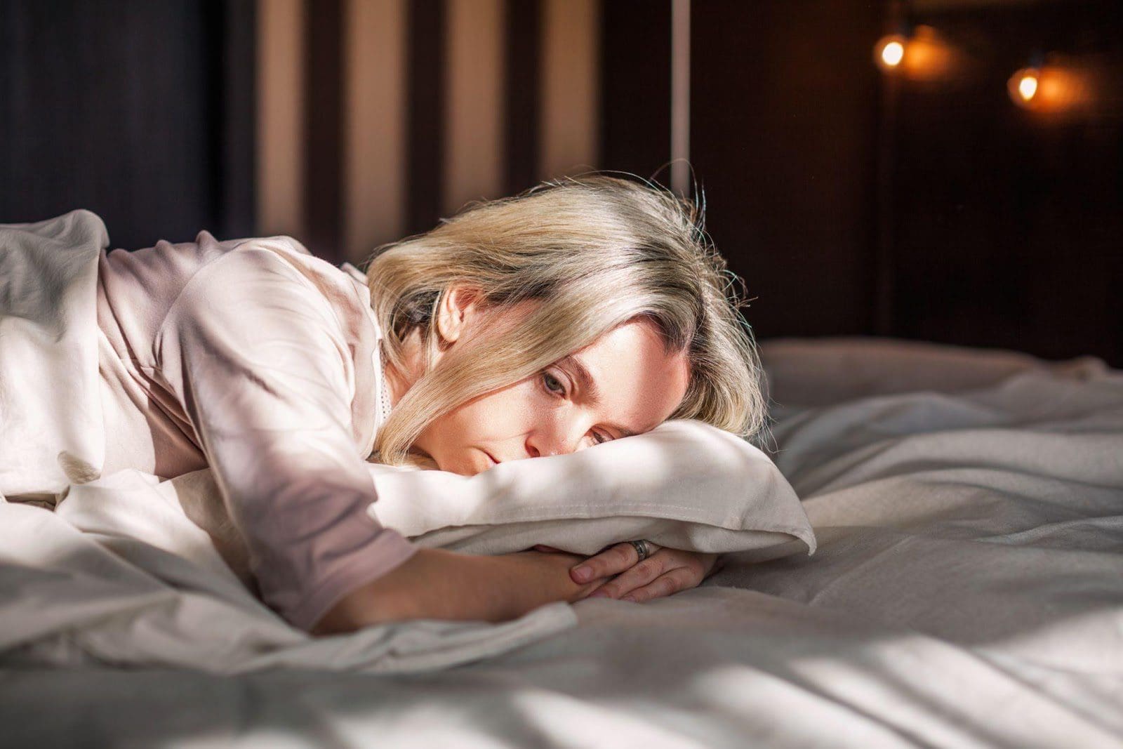 Woman with insomnia lying on her stomach in bed.