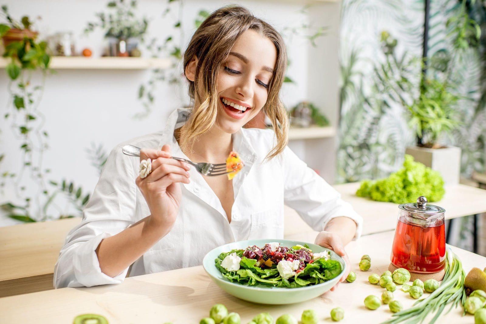 Young woman eating a salad at her kitchen table.