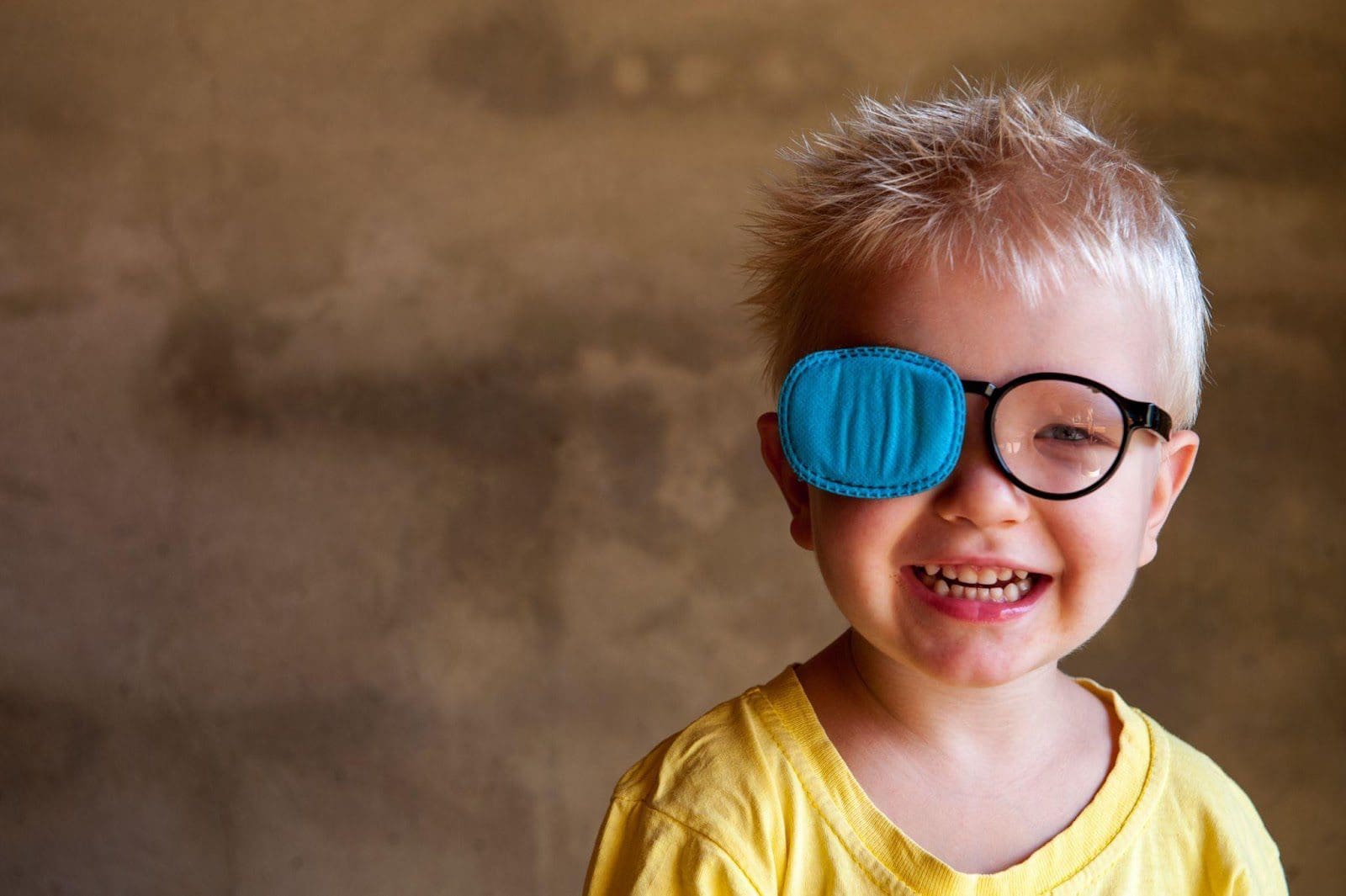 Little boy wearing glasses with an eye patch over one lens.